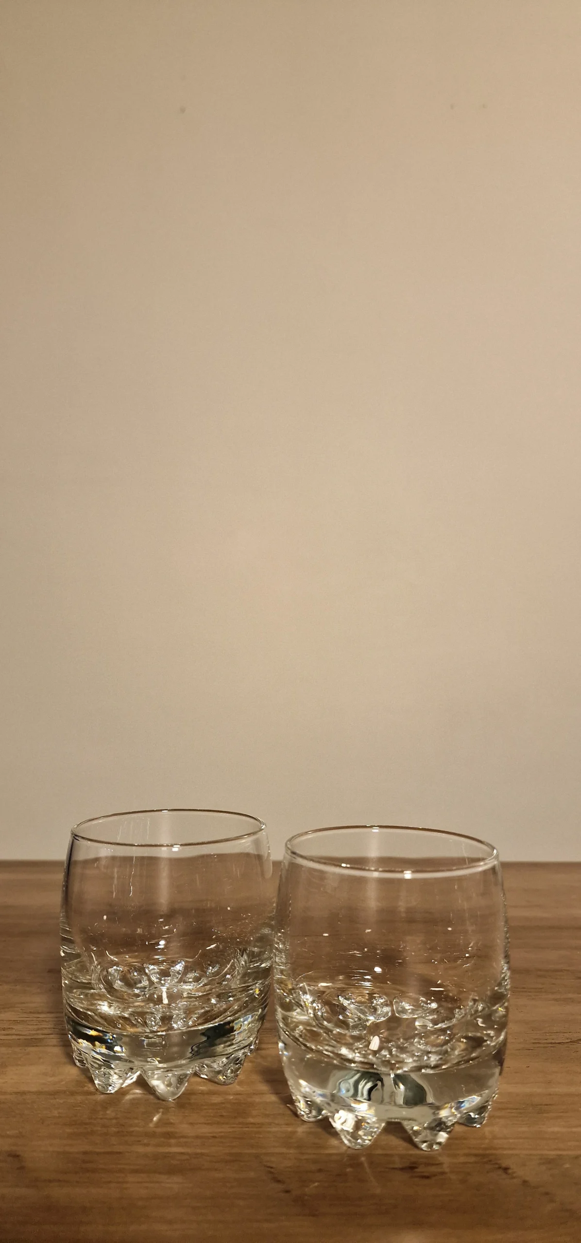 Två klara glas med dekorativa bottnar, perfekt för servering av drycker. Stilren design för moderna hem